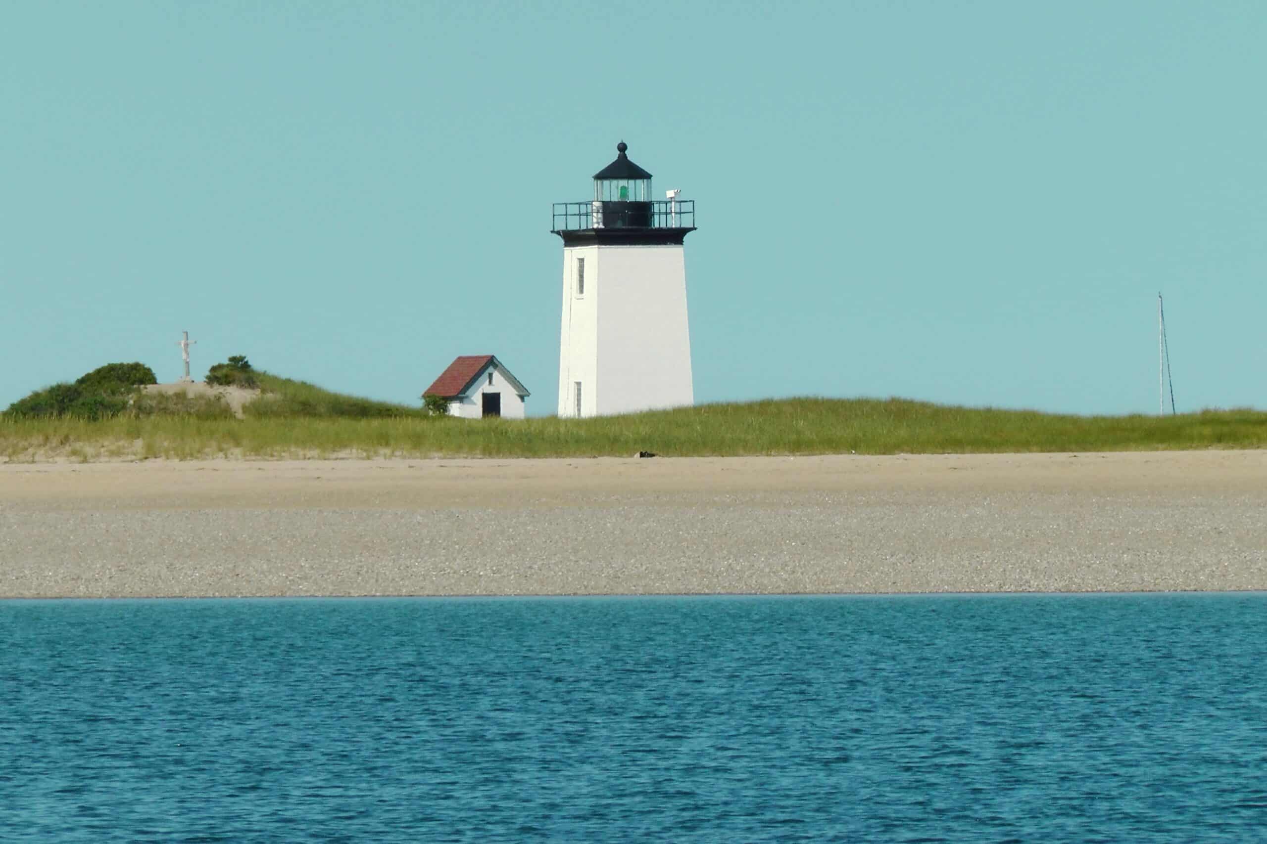 A lighthouse sits on the shore of a body of water.