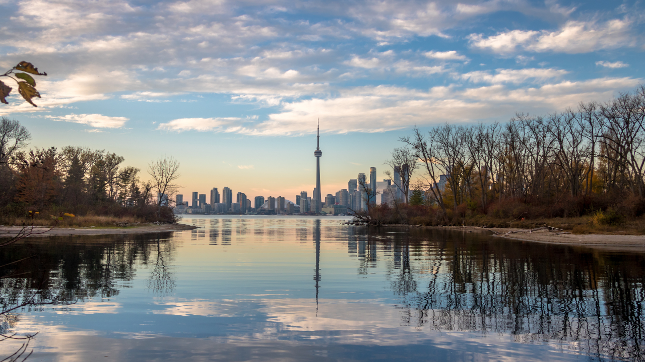 A city skyline, such as Toronto, reflected in a body of water.